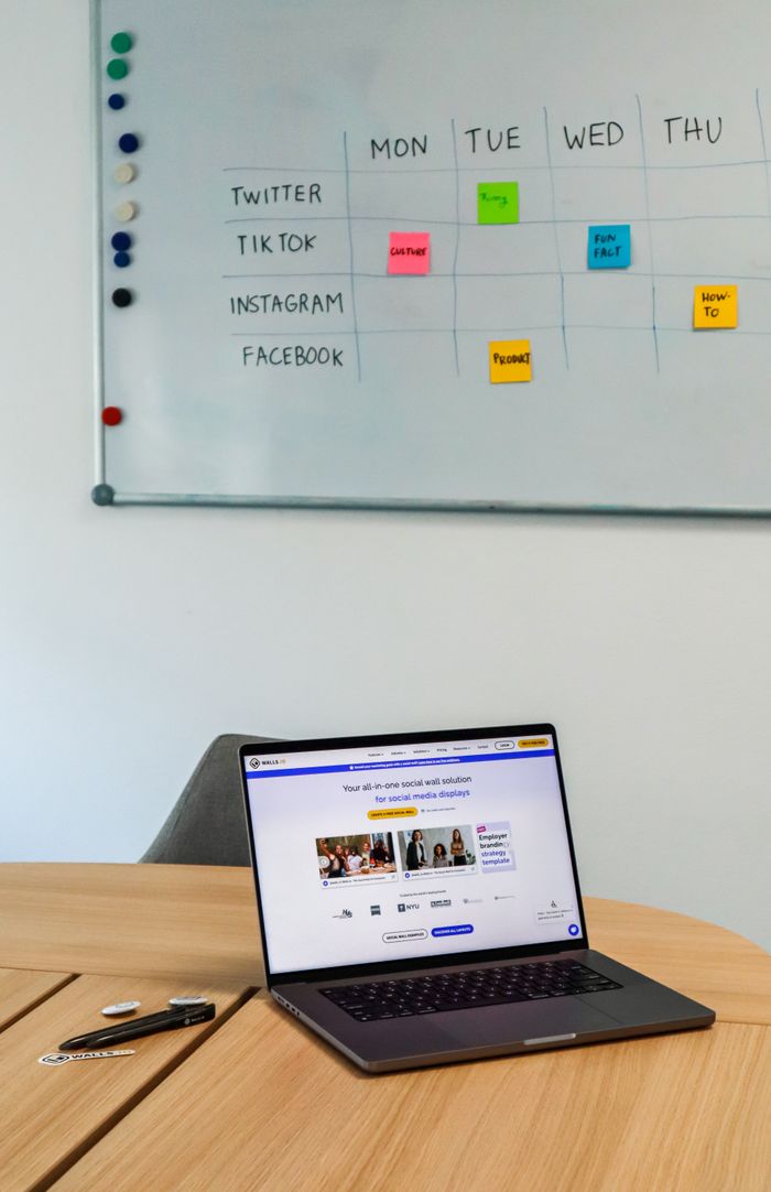 about-hero A modern office setup featuring a laptop and a whiteboard schedule for social media platforms.